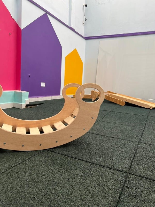 Sala de movimento da Cardim Kids com rampa de escalada de madeira, piso emborrachado e painel colorido na parede