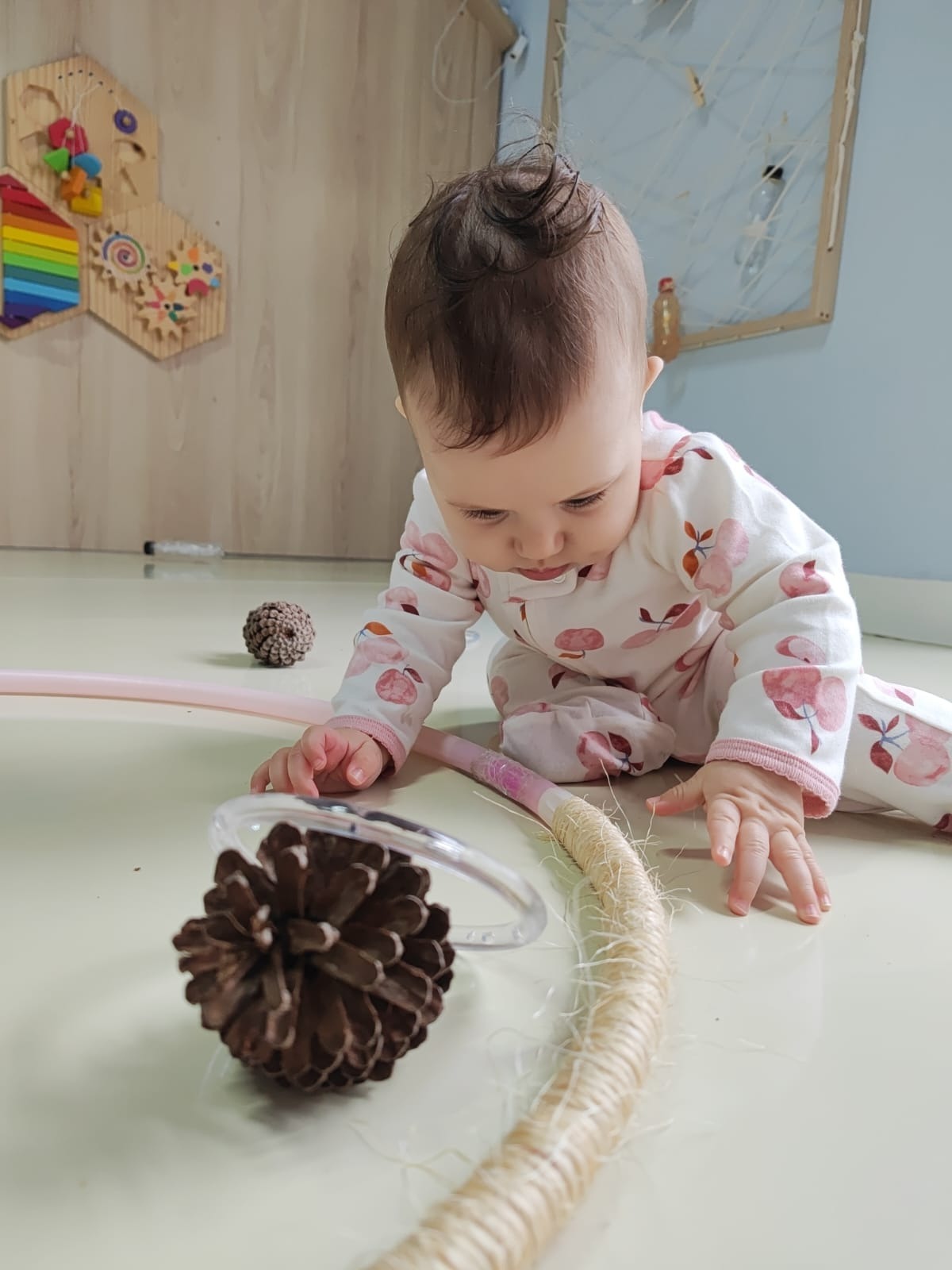 Bebê da Cardim Kids explorando materiais naturais e brinquedos de madeira no chão da sala